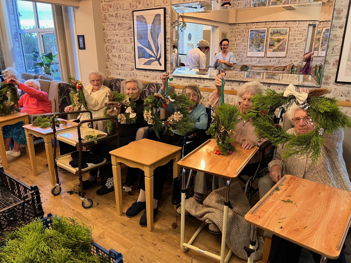 Image of some of the residents of Alsley Lodge Care Home holding up Christmas wreaths that they created with us when we visited them in December.